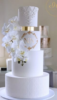 a three tiered white wedding cake with gold accents and flowers on the top layer