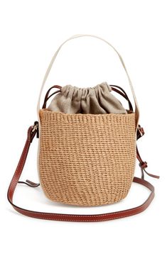 Elevate your warm-weather look with this compact basket bag handwoven by independent craftswomen in Kenya from partially upcycled materials. A drawstring lining keeps items secured, while a leather strap and logo-embellished Woody strap offer carrying options. Drawstring closure Top carry handle; adjustable shoulder strap Paper with textile and leather trim Due to the handmade nature, each item is one of a kind Made in Kenya Designer Handbags This product is Fair Trade Certified™ and was made us Beige Woven Leather Bucket Bag, Natural Woven Leather Bucket Bag, Eco-friendly Bucket Bag With Braided Top Handle, Beige Woven Leather Crossbody Bucket Bag, Eco-friendly Woven Bucket Bag With Top Handle, Chic Woven Bucket Crochet Bag, Everyday Beige Basket Bucket Bag, Chic Woven Crochet Bucket Bag, Casual Crochet Bucket Bag With Leather Handles