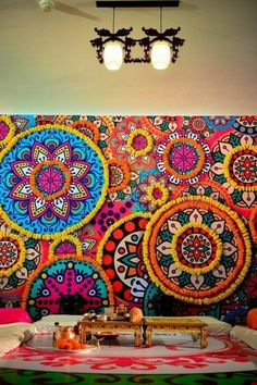 an artisticly decorated room with bright colors on the wall and colorful artwork hanging above it