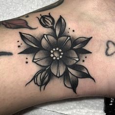 a black and white flower tattoo on the left side of the foot, with hearts in the background