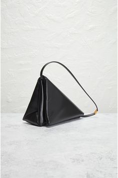 Find MARNI Prisma Triangle Bag on Editorialist. Marni Prisma Triangle Bag in Black Leather exterior with vegan leather lining. Made in Italy. Flap top with zip closure. Two compartments. Gold-tone hardware. Measures approx 11 W x 7.25 H x 4.75 D Shoulder strap with a 8.75 drop. Excellent. Minor signs of wear throughout. Original brand box and authenticity card not included. FNEF-MY7. SBMQ0087U0-P6039-00N99. About the designer: