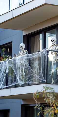 Two skeleton decorations with spider webs on a balcony. Diy House Halloween Decorations, Diy Halloween Balcony Decorations, Halloween Decorations For Apartments Balcony, Balcony Halloween Ideas Apartment, Apartment Patio Halloween Ideas, Halloween Apartment Patio Decor, Townhouse Halloween Decorations Outdoor, Halloween Apartment Decor Balcony, Apartment Patio Halloween Decor