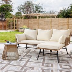 a couch sitting on top of a rug next to a table and chair in front of a wooden fence