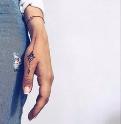 a woman's left hand with a small tattoo on the middle finger and an arrow in the middle