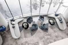 an aerial view of some chairs and tables in a room with glass walls that look like they are floating on water