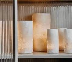 some white candles sitting on top of a shelf