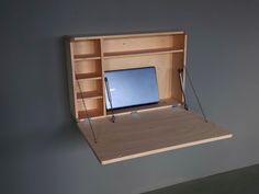 a wooden desk with a laptop on it and some shelves in the wall behind it