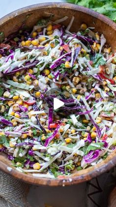 a wooden bowl filled with coleslaw and corn