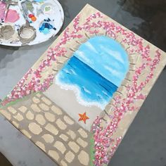 a painting is being displayed on a table next to a plate with paintbrushes