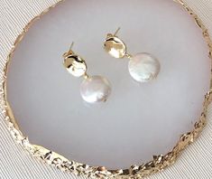 Gold Pearl Earrings are a hammered gold stud with gorgeous freshwater pearl coin bead drop. The earring measures approximately 2.8cm from top of gold stud section. The earring fixing  is made from gold plated hammered gold.  These Gold Pearl Earrings would make a wonderful gift for your bridesmaids too! And they are not just for weddings either - why not wear them on a night out.? They also make a fabulous gift! They are beautifully packaged in a pretty white or grey velvet pouch. NOTE: THIS ITEM TAKES APPROXIMATELY 1 WEEK TO COMPLETE - IF YOU REQUIRE IT SOONER, PLEASE CONTACT US BEFORE PLACING YOUR ORDER. Elegant Hammered Earrings For Wedding, Elegant Hammered Wedding Earrings, Hammered Drop Earrings For Wedding, Hammered Drop Pearl Earrings As Gift, Hammered Gold Plated Earrings For Wedding, Hammered Gold Plated Wedding Earrings, Hammered Gold-plated Earrings For Wedding, Elegant Hammered Pearl Earrings For Wedding, Minimalist Hammered Earrings For Wedding