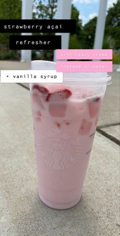 a pink drink with strawberries in it sitting on the ground