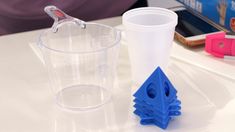 two plastic cups sitting on top of a table next to each other, one with a toothbrush in it