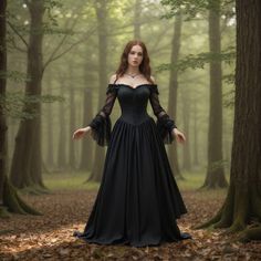 a woman in a black dress is standing in the woods with her hands on her hips