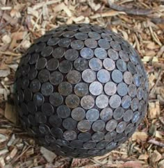 a large metal ball sitting in the middle of some wood mulch with words above it