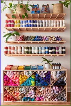 a wooden shelf filled with lots of different colored yarns and paint bottles next to a potted plant