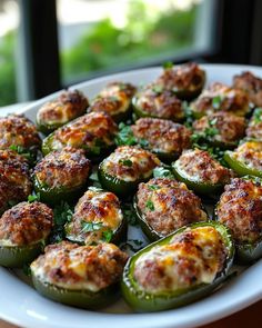 a white plate topped with stuffed peppers covered in meatballs and parmesan cheese