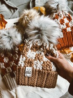 a person is holding a knitted hat with two pom poms on it