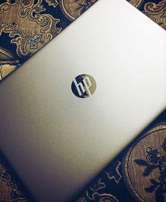 an hp laptop sitting on top of a bed covered in damasks and paisley