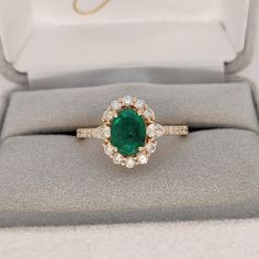 an emerald and diamond ring in a box