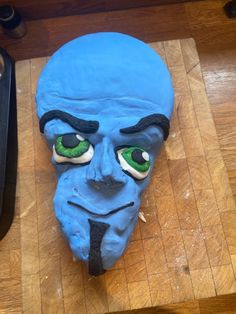 a blue mask with green eyes on a wooden table