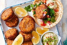 some food is sitting on a plate with lemon wedges and other foods around it