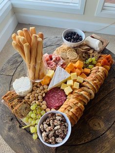 an assortment of cheeses, crackers and meats on a wooden platter