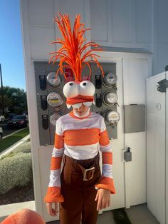 a man in an orange and white costume standing next to a parking meter