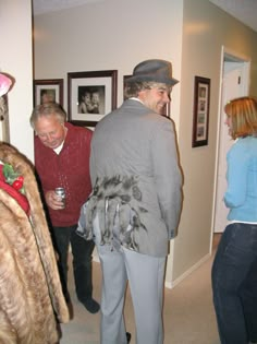 some people are standing in a hallway and one is wearing a fur coat, the other has a hat