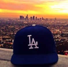 a los angeles dodgers cap sitting on top of a ledge in front of the city