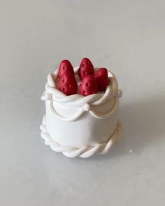 four strawberries are placed in a small white bowl on a gray surface, with rope around the edges