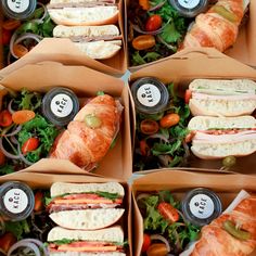 four boxes filled with sandwiches and salads on top of each other's sides