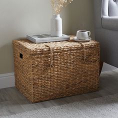 a wicker trunk is sitting on the floor next to a coffee table