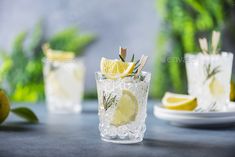 two glasses filled with lemonade and rosemary garnish on top of a table