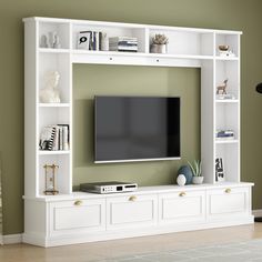 a flat screen tv sitting on top of a white entertainment center next to a book shelf