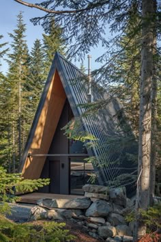 a triangular shaped house in the woods with rocks and trees around it, surrounded by evergreens