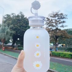 a hand holding a water bottle with flowers painted on the side and a flower in the top