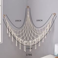 a white hammock hanging on the wall next to a window with measurements for it