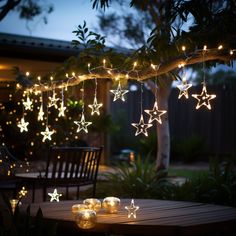 some lights that are hanging from a tree branch in the night time with stars on them