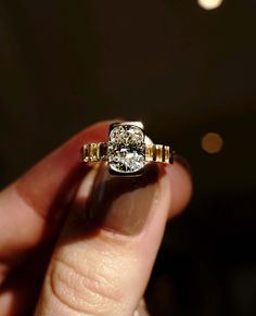 a person holding a ring with a diamond in it's middle and two yellow bands around the band