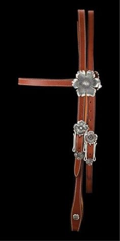 a horse bridle with silver flowers on the side and brown leather belt around it