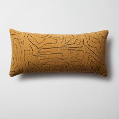 a yellow pillow with an abstract design on the front and back, sitting on a white surface