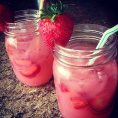 two mason jars with strawberries in them sitting on a counter