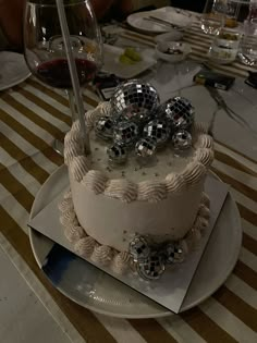 a white cake sitting on top of a table covered in disco balls and silver confetti