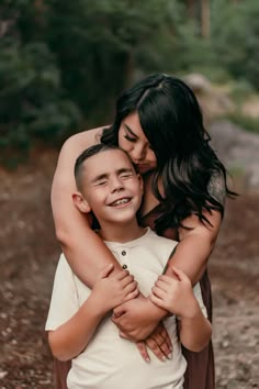 a woman hugging a boy in the woods