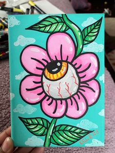 a painting of a pink flower with green leaves and an eyeball in the center