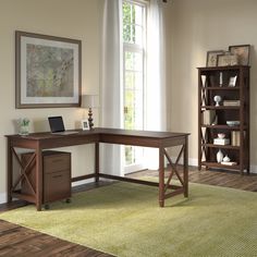 a computer desk sitting on top of a green rug in front of a large window