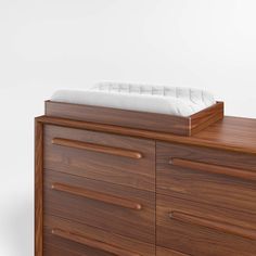 a wooden dresser with a white mattress on top