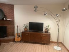 a living room with a television, guitar and lamp on the floor next to a fireplace