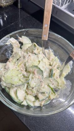 a glass bowl filled with cucumber salad on top of a counter