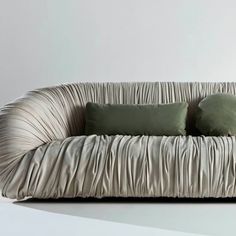 a couch with two pillows on it and one pillow is folded in the shape of a wave